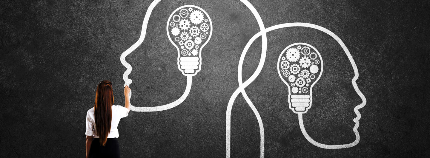 Businesswoman drawing human heads with light bulbs and gears 