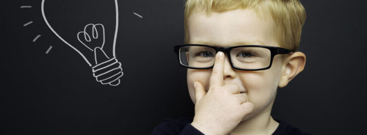 A boy picks up his glasses and next to him is a cartoon light bulb