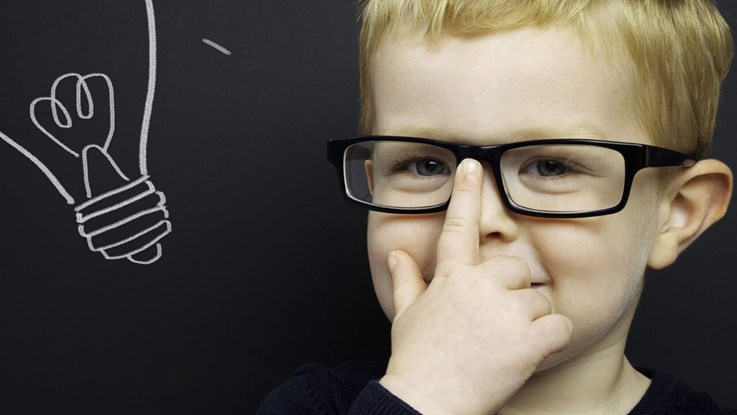 A boy picks up his glasses and next to him is a cartoon light bulb
