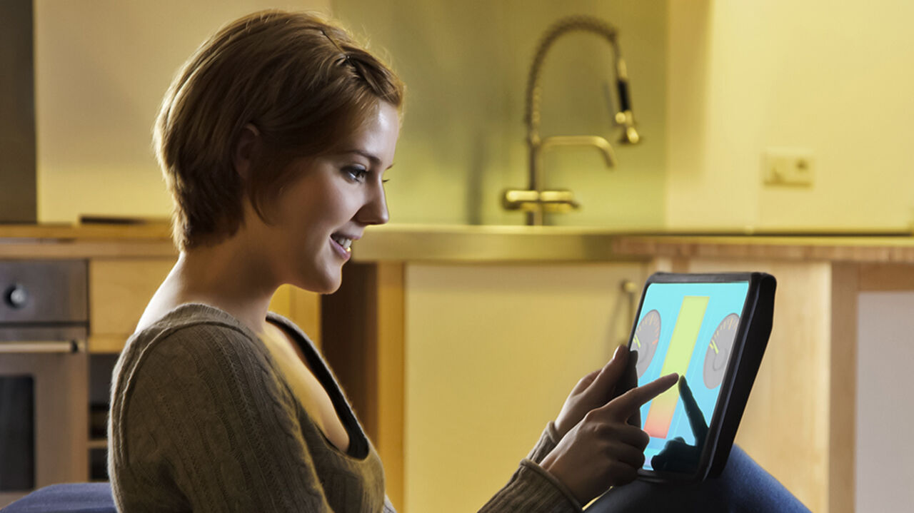 Woman sitting on a couch holding a Smart Energy Controller